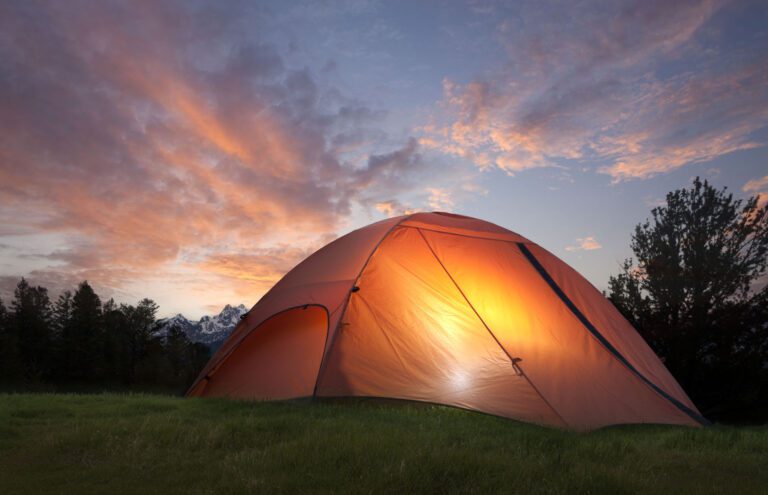 Tent with light inside at dusk near the Grand Teton mountains